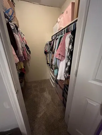 a view of walk in closet with clothes and shoes