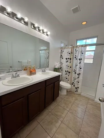 a bathroom with a double vanity sink mirror and toilet
