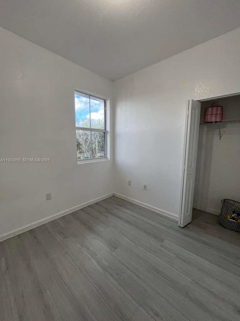11665 Southwest 244 Street, Unit 116 Homestead, FL 33032 - Photo 22 of 32 an empty room with wooden floor and windows
