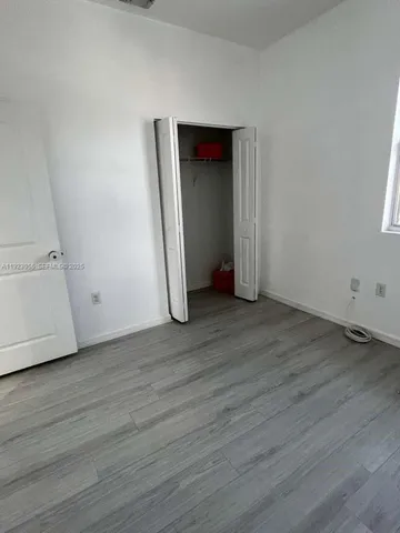 a view of an empty room with wooden floor and closet