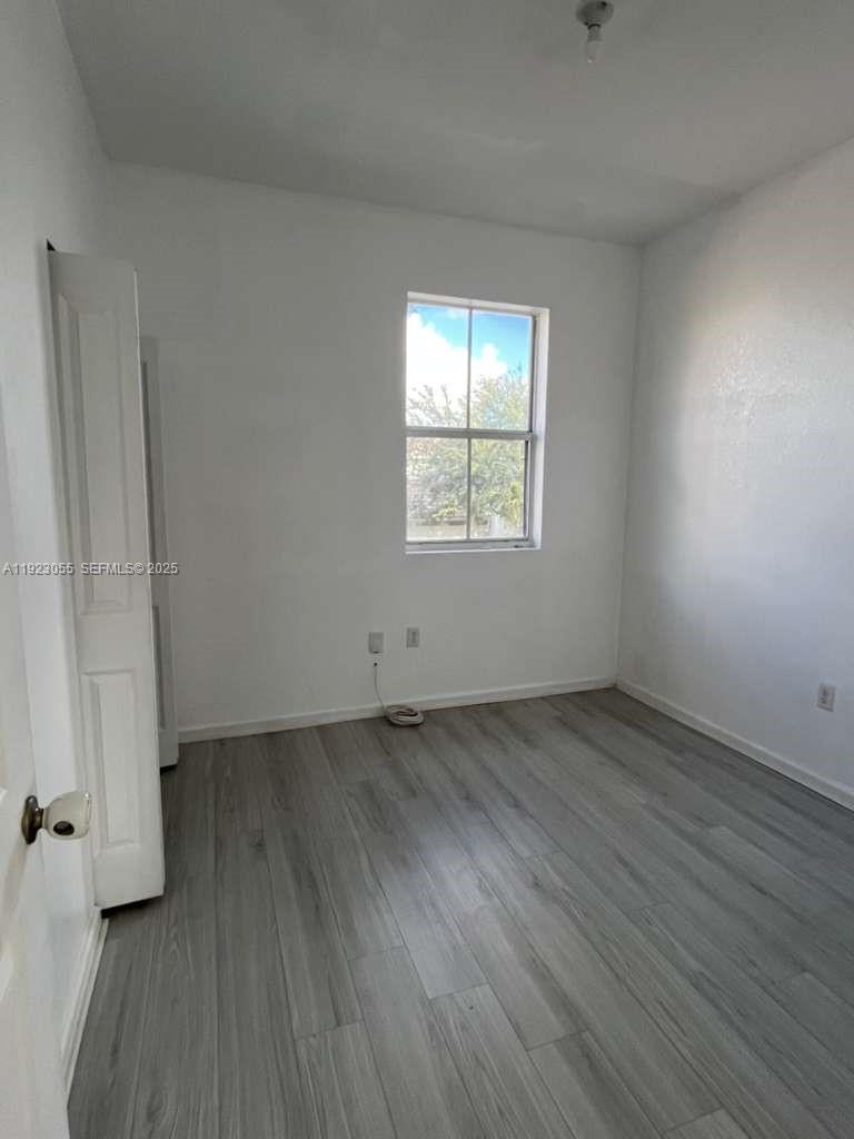 11665 Southwest 244 Street, Unit 116 Homestead, FL 33032 - Photo 28 of 32 an empty room with wooden floor and windows