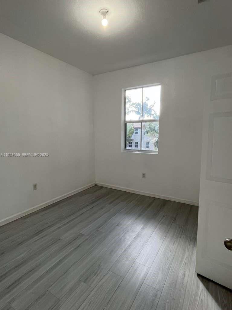 11665 Southwest 244 Street, Unit 116 Homestead, FL 33032 - Photo 29 of 32 an empty room with wooden floor and windows