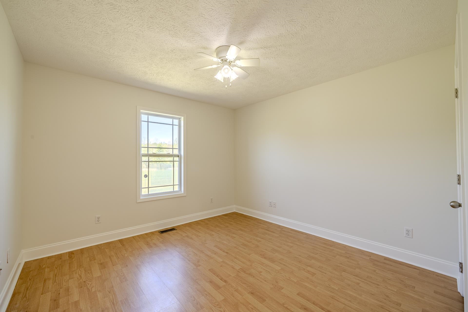 200 Boyd Road Adamsville, TN 38310 - Photo 18 of 26 an empty room with wooden floor fan and windows