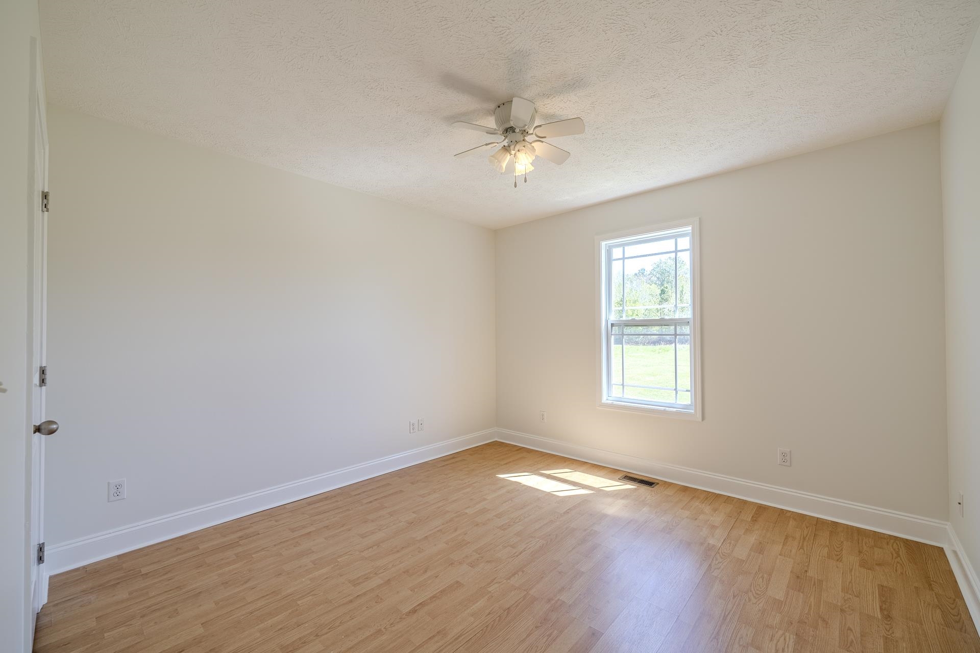 200 Boyd Road Adamsville, TN 38310 - Photo 10 of 26 an empty room with wooden floor fan and windows