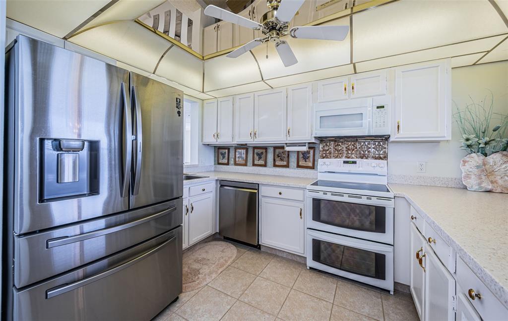 17940 Gulf Boulevard, Unit 7B Redington Shores, FL 33708 - Photo 27 of 58 a kitchen with stainless steel appliances a refrigerator sink and cabinets