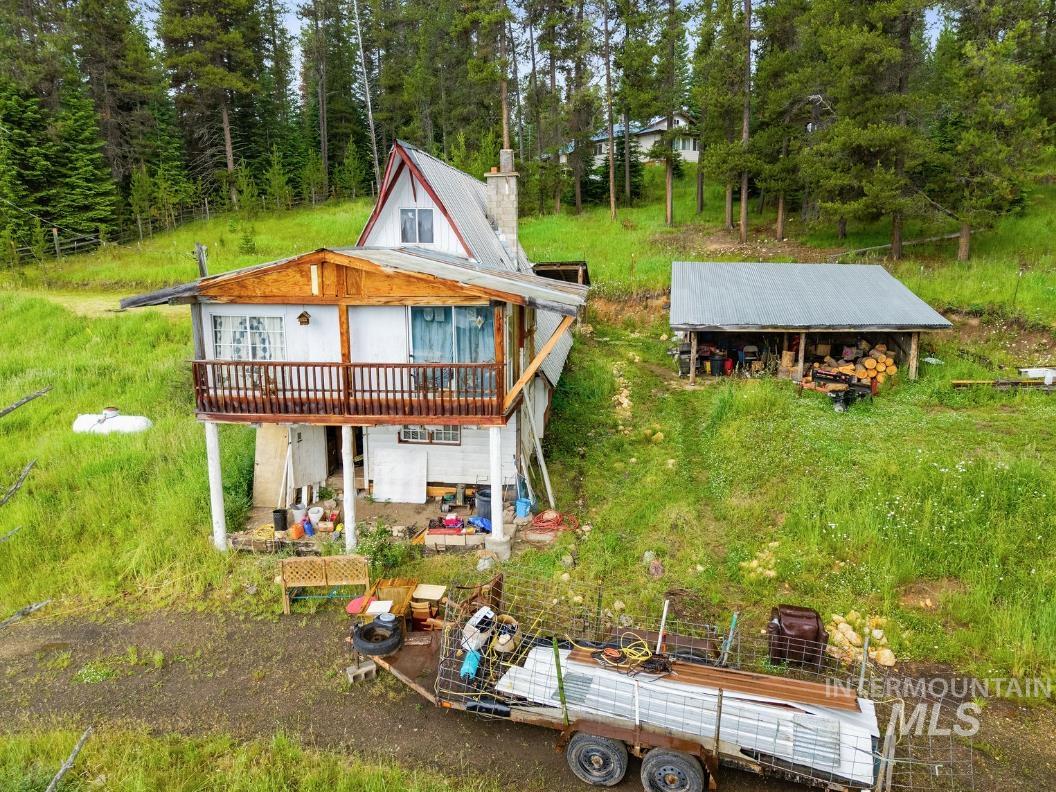 101 Hidden Springs Road Elk City, ID 83525 - Photo 1 of 28 Hillside home featuring a second-story balcony with wood railing, a gable roofline, and a detached open-front shed with a metal roof