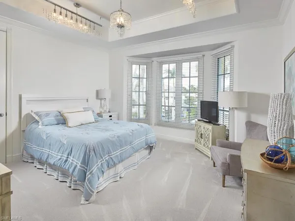 a spacious bedroom with a bed couch and windows