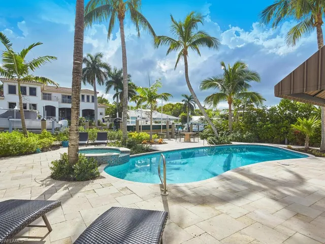 a view of swimming pool with a lawn chairs under palm trees