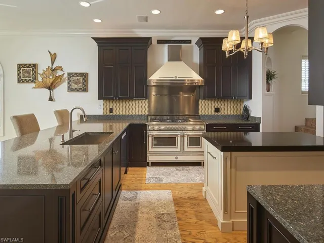 a kitchen with stainless steel appliances granite countertop a sink a stove and a wooden cabinets