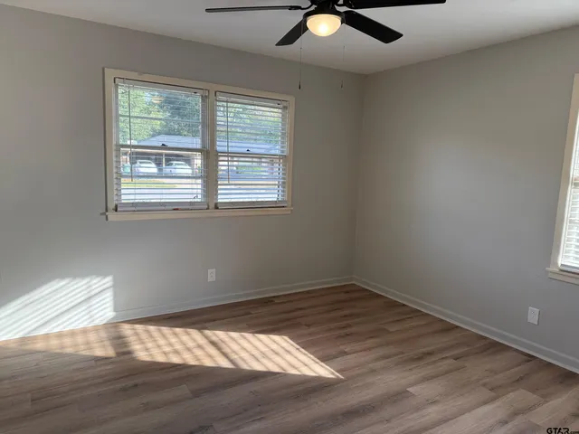 an empty room with wooden floor and a ceiling fan