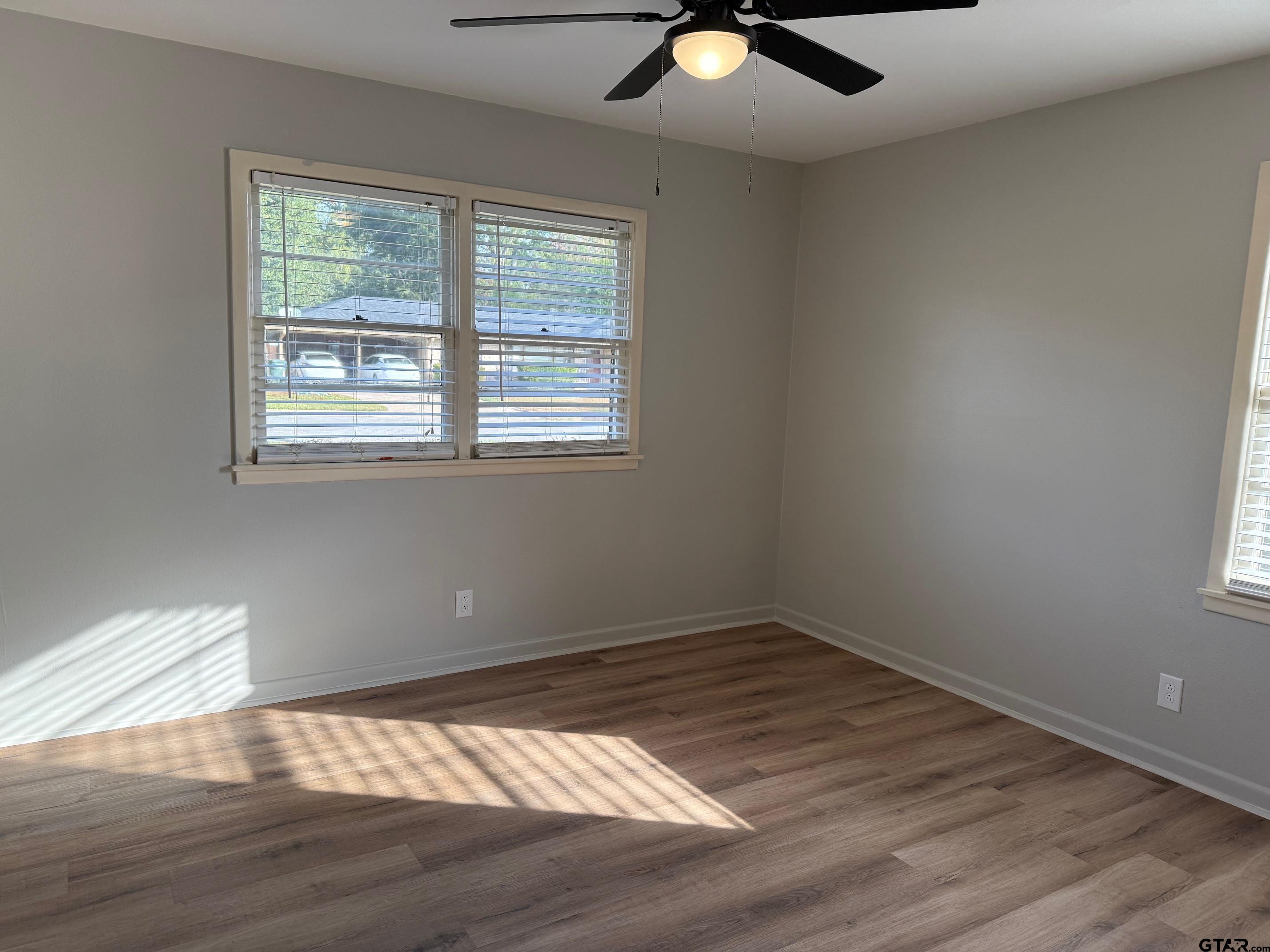 301 Ridgecrest Drive Tyler, TX 75701 - Photo 15 of 27 an empty room with wooden floor fan and windows