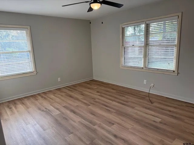 a view of an empty room with wooden floor and a window