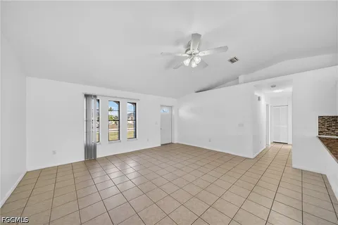 a view of an empty room with window and chandelier fan