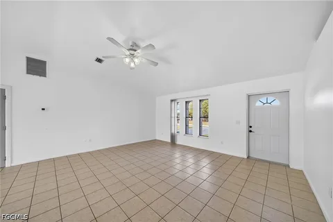 a view of an empty room with chandelier fan