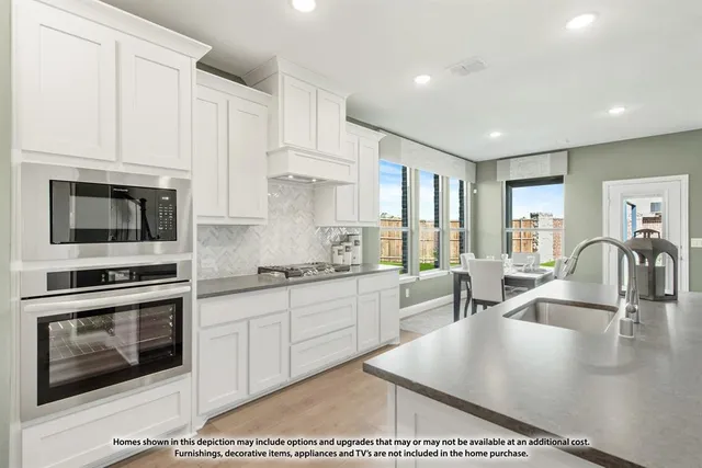 a kitchen with stainless steel appliances granite countertop a stove a sink a refrigerator and white cabinets