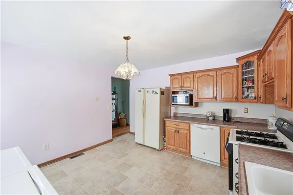 a kitchen with stainless steel appliances a sink a stove a refrigerator cabinets and a dining table