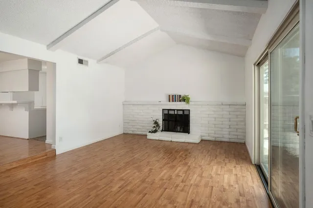 a view of empty room with wooden floor and fireplace