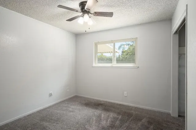 an empty room with windows and fan