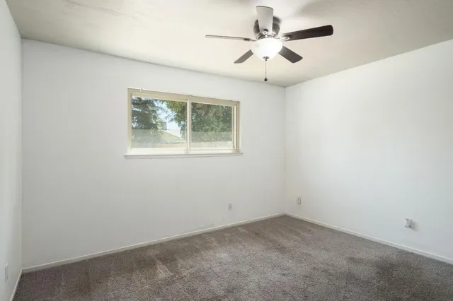an empty room with a window and a fan