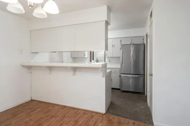 a view of a refrigerator in kitchen and white cabinets