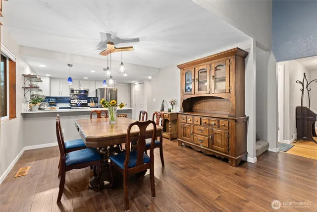 a dining area with stainless steel appliances a dining table chairs and couches