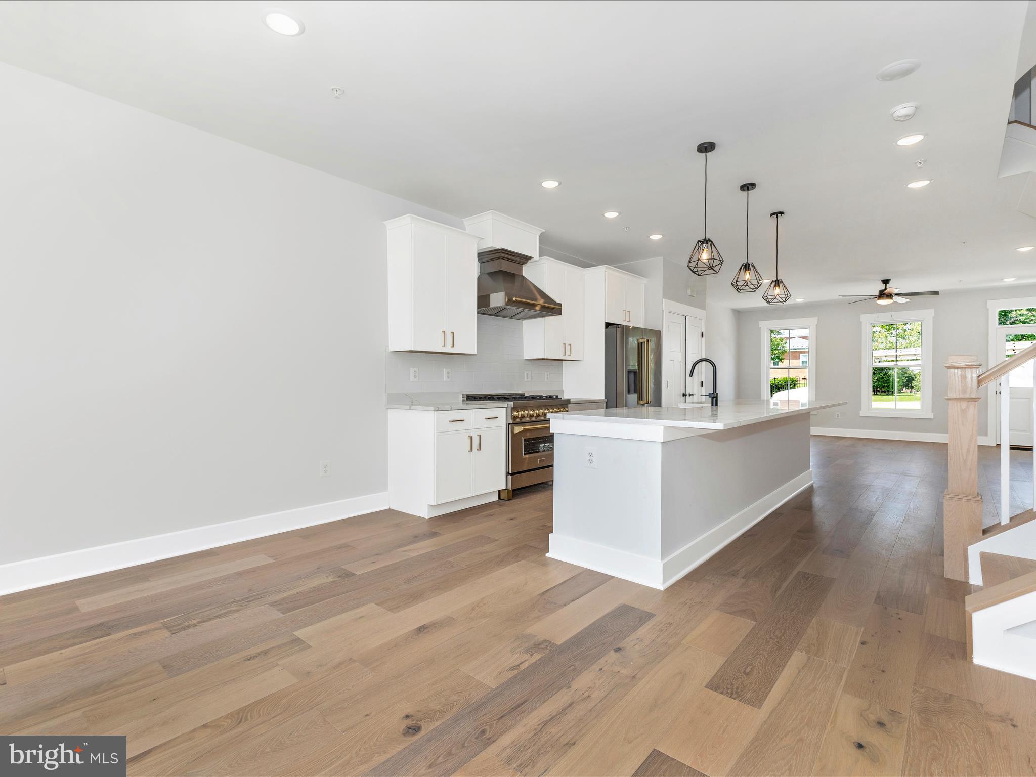 252 South Carroll Street Frederick, MD 21701 - Photo 18 of 68 a large white kitchen with wooden floors and stainless steel appliances