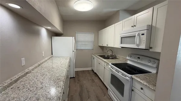a kitchen with granite countertop white cabinets and white appliances