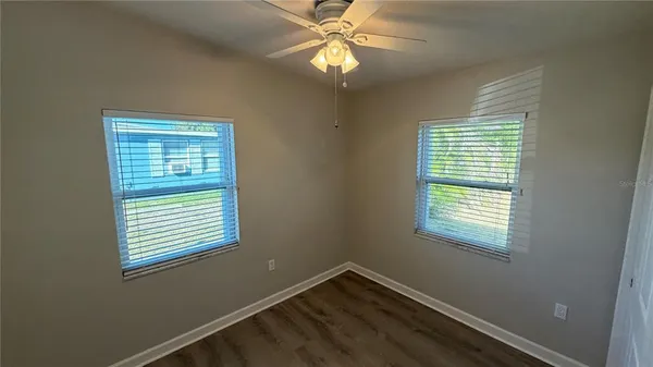 a view of an empty room with window and chandelier fan