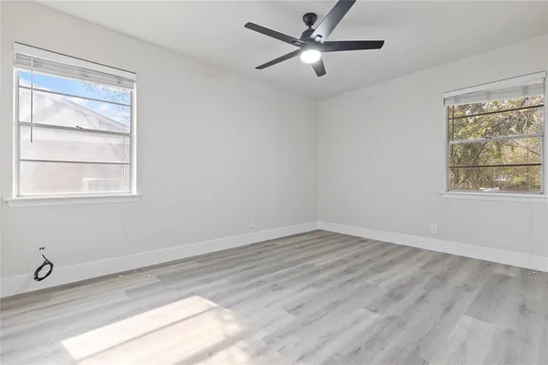 a view of an empty room with a window and wooden floor