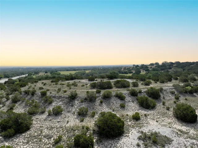 a view of a dry field with trees in the background
