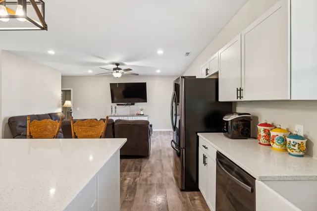 a kitchen with stainless steel appliances granite countertop a stove top oven a sink a dining table and chairs with white cabinets