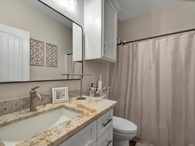 a bathroom with a granite countertop sink a toilet and a mirror