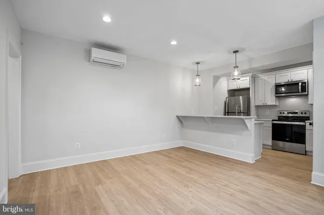 a kitchen with stainless steel appliances white cabinets and a stove a refrigerator with wooden floors