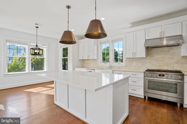 a kitchen with stainless steel appliances granite countertop a sink a stove and a wooden floor