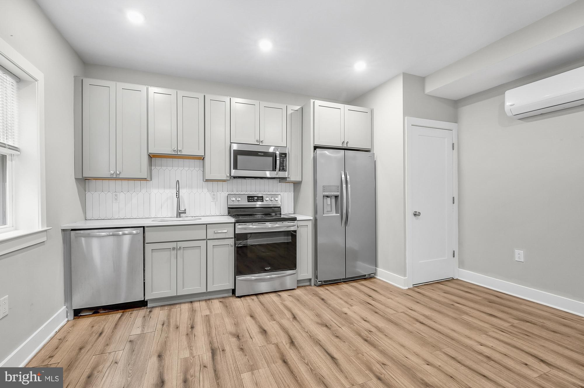 5007 Pentridge Street, Unit 1C Philadelphia, PA 19143 - Photo 3 of 14 a kitchen with a refrigerator a stove top oven a sink and cabinets