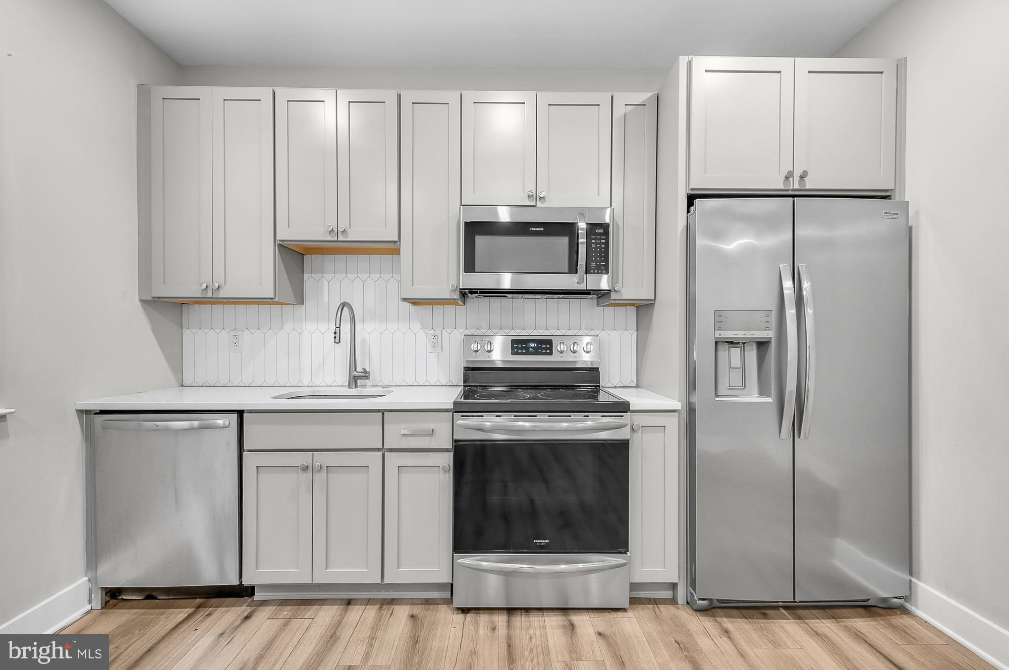 5007 Pentridge Street, Unit 1C Philadelphia, PA 19143 - Photo 7 of 14 a kitchen with white cabinets stainless steel appliances and a refrigerator