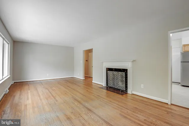 a view of empty room with wooden floor and fireplace