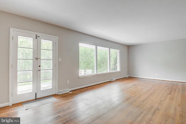 a view of an empty room with a window and wooden floor