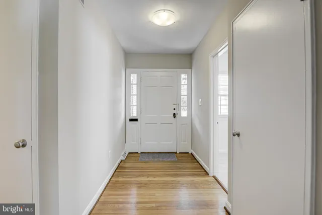 a view of a hallway with wooden floor and a bathroom