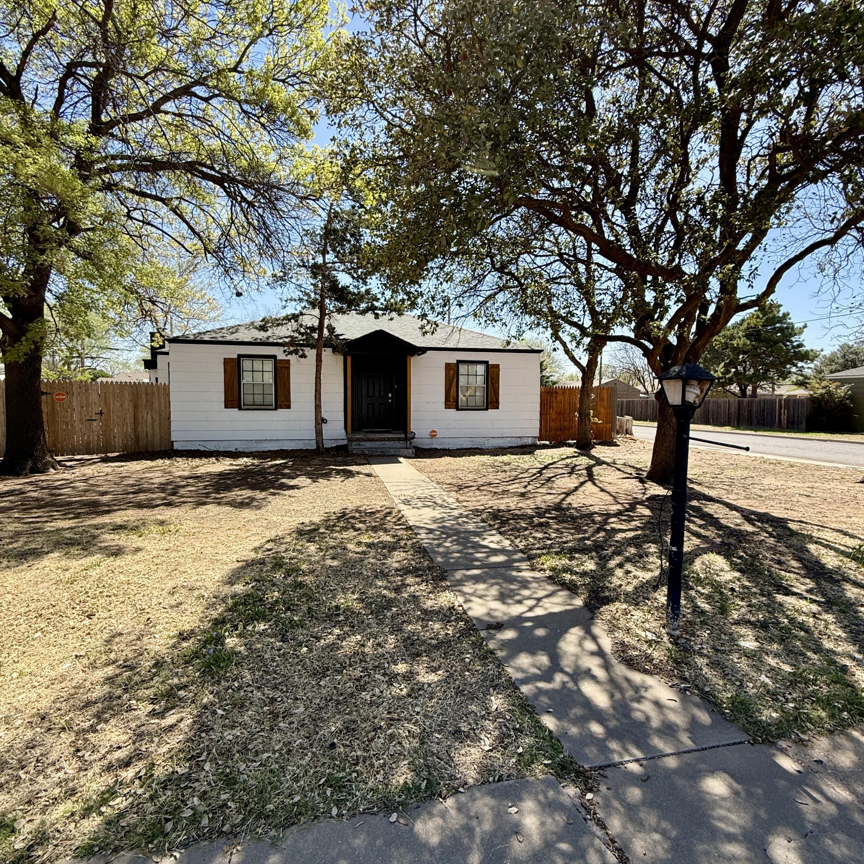 2517 28th Street Lubbock, TX 79410 - Photo 1 of 2 a backyard of a house with large trees and covered with wooden fence