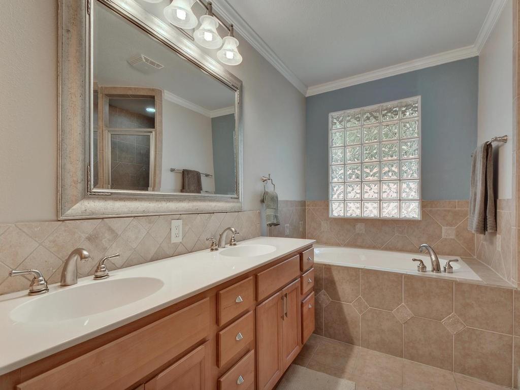 610 West N Loop Boulevard Austin, TX 78751 - Photo 15 of 29 The bathroom features a dual vanity with light-colored cabinetry, a large framed mirror, and a bathtub with tile surround