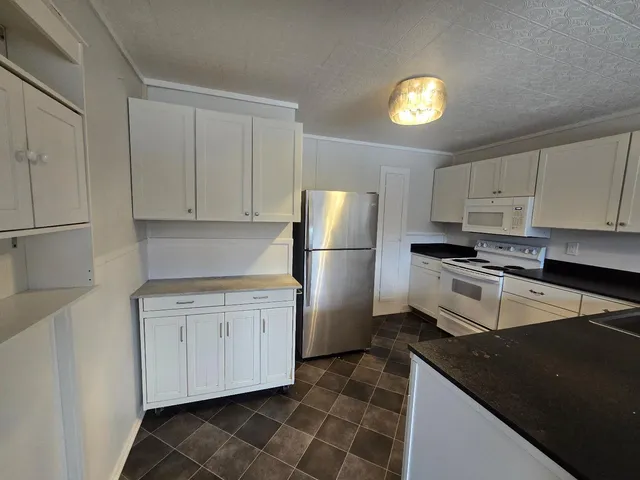 a kitchen with granite countertop white cabinets and stainless steel appliances