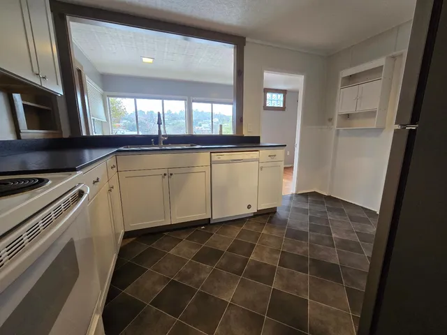 a kitchen with a sink a stove a window and cabinets