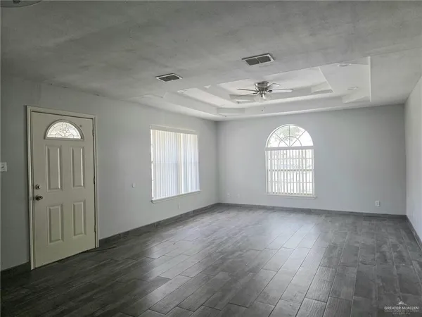 a view of an empty room with a window and wooden floor