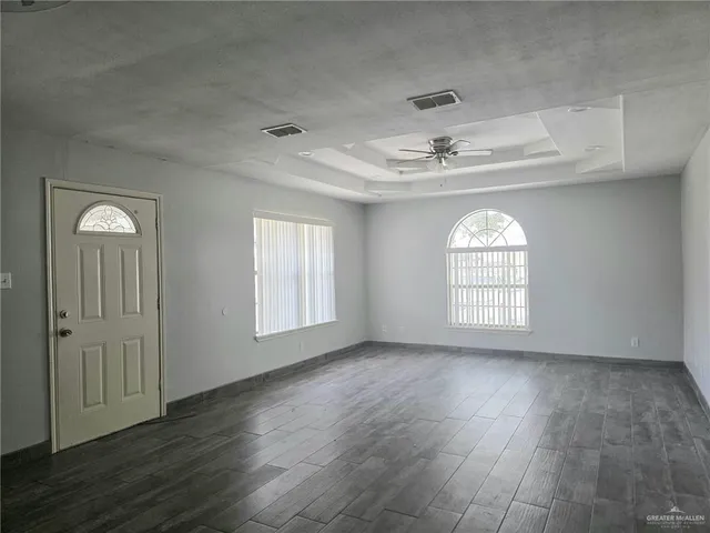 a view of an empty room with a window and wooden floor
