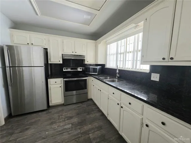 a kitchen with granite countertop a refrigerator a sink a stove a microwave and cabinets