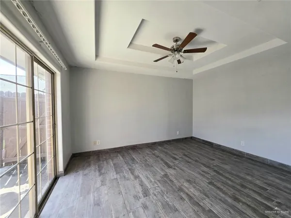 an empty room with wooden floor fan and windows