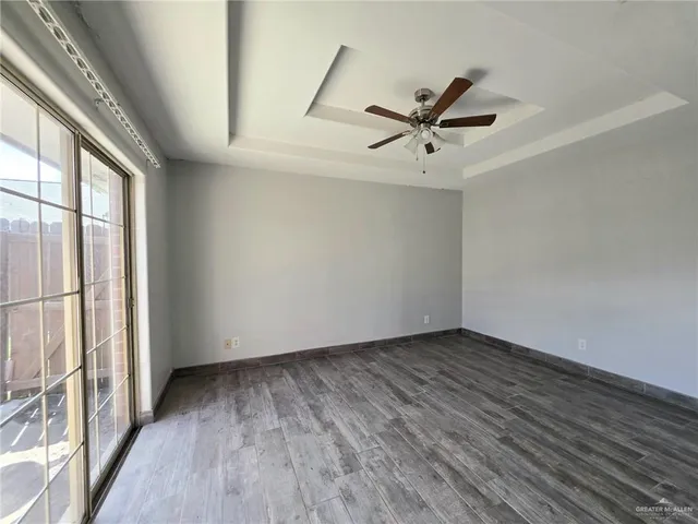 an empty room with wooden floor fan and windows