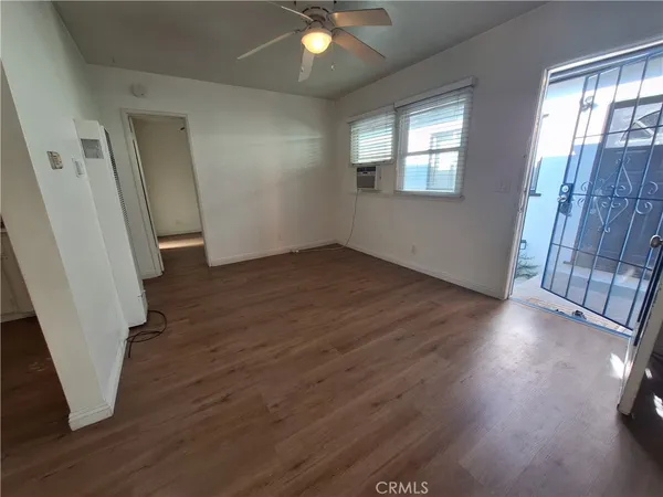 a kitchen with granite countertop a stove top oven a sink dishwasher a refrigerator and white cabinets with wooden floor