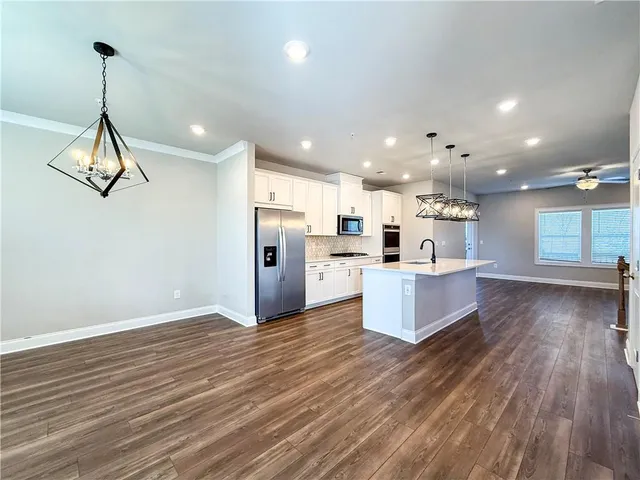 a large kitchen with a large counter top a sink stainless steel appliances and cabinets